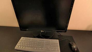 Een computeropstelling met een beeldscherm, toetsenbord en muis op een bureau.