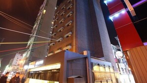 A modern hotel with a prominent entrance and a sign indicating a grand opening.