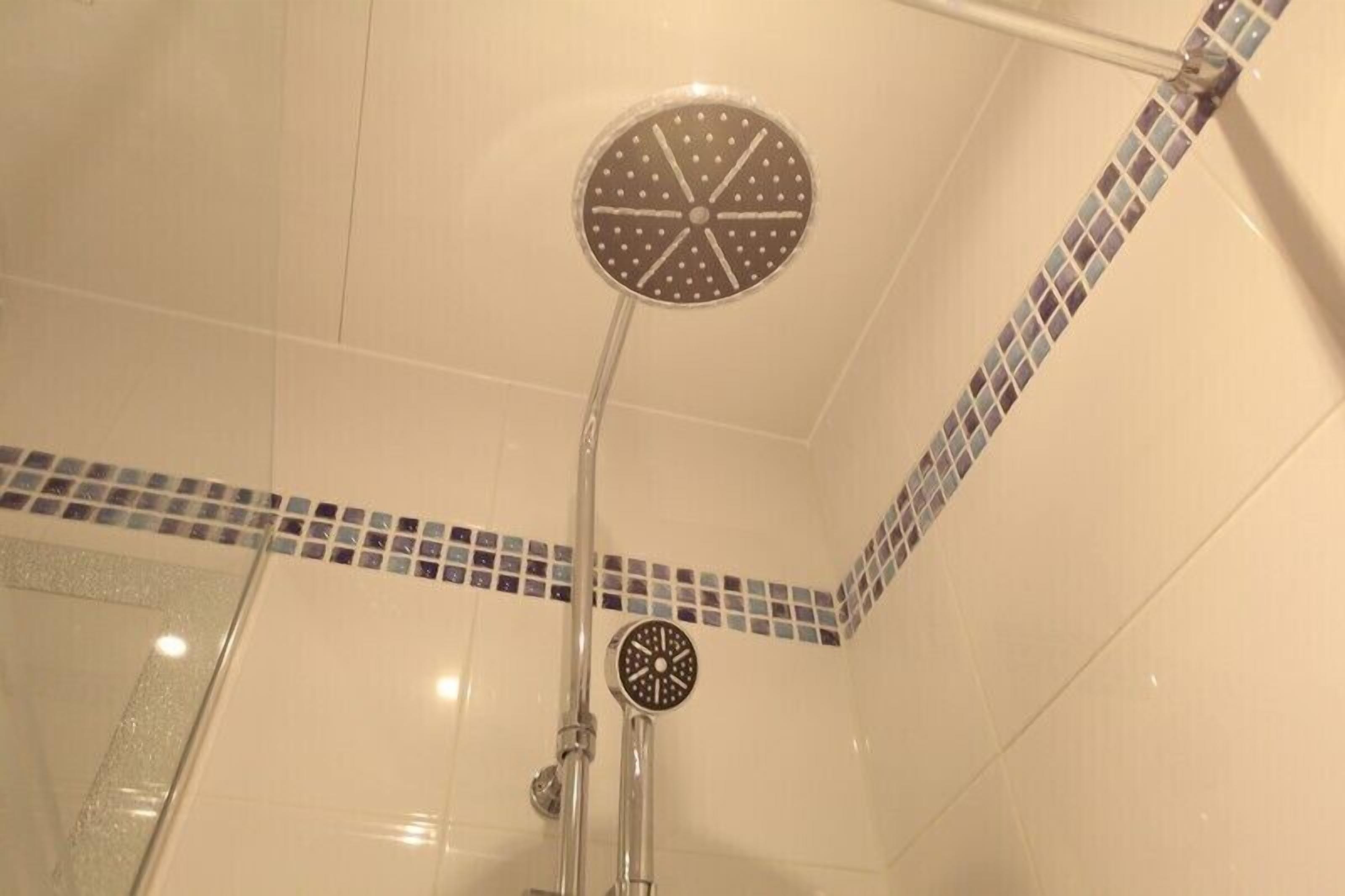 A shower with a circular head and a handheld showerhead.