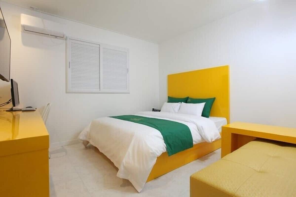 A modern hotel room with a bed, a desk, and a chair.