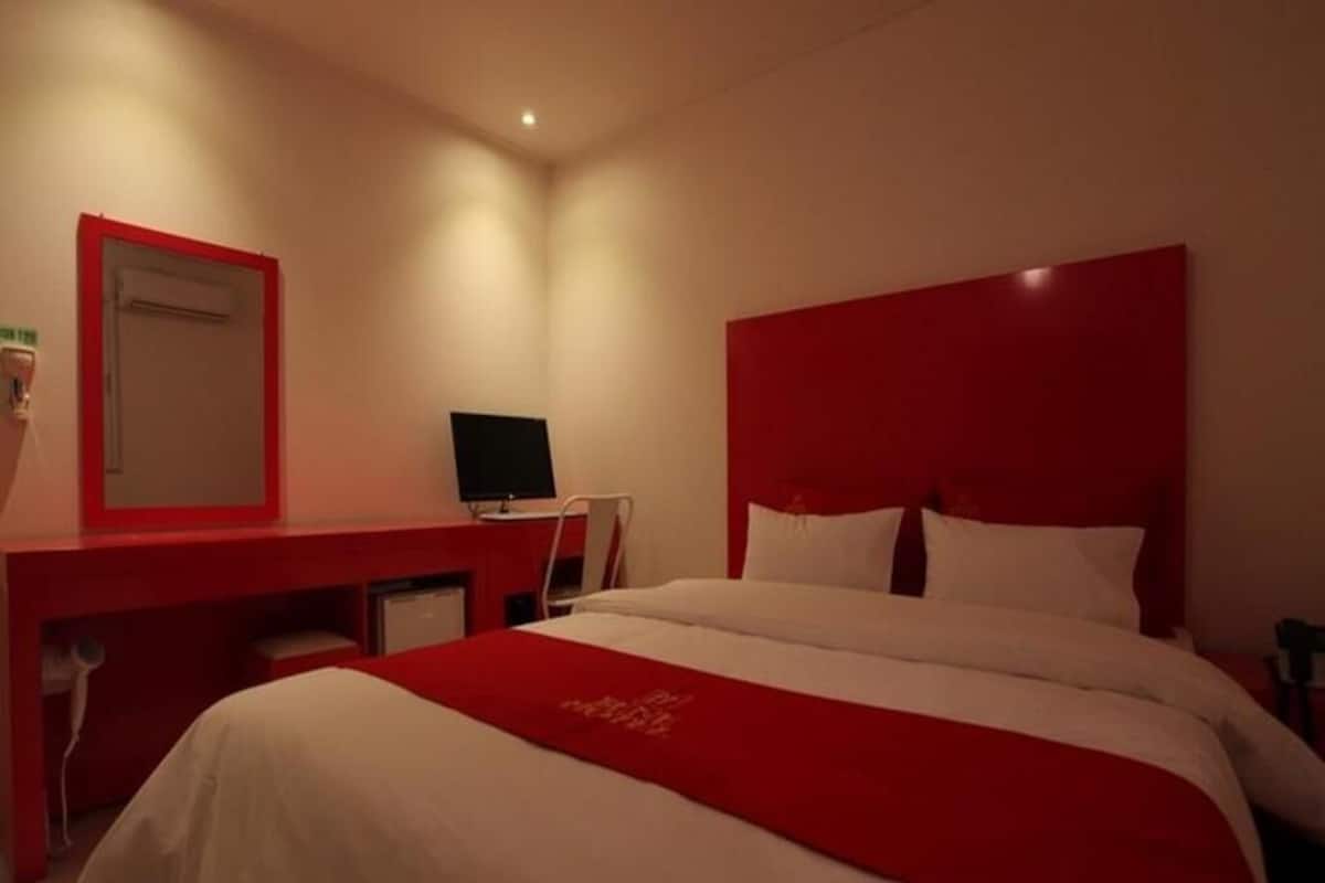 A hotel room with a bed, a desk, and a television.