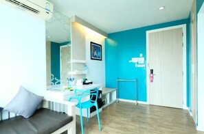 A room with a white desk, a blue chair, a white sofa, a door, and a wall-mounted air conditioning unit. - Sunday Beachfront View Jomtien Pattaya (Pattaya)