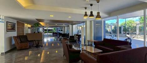 A spacious lobby with seating areas, a reception desk, and large windows offering a view of the outdoors.