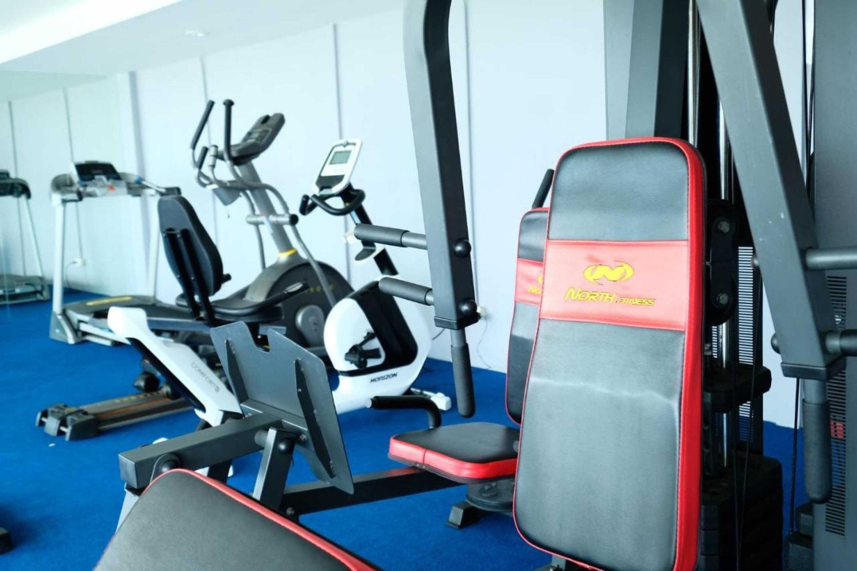 Ein Fitnessstudio mit verschiedenen Trainingsgeräten, darunter Laufbänder, Crosstrainer und Kraftgeräte.