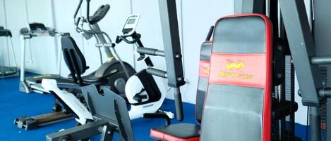 Ein Fitnessstudio mit verschiedenen Trainingsgeräten, darunter Laufbänder, Crosstrainer und Kraftgeräte.