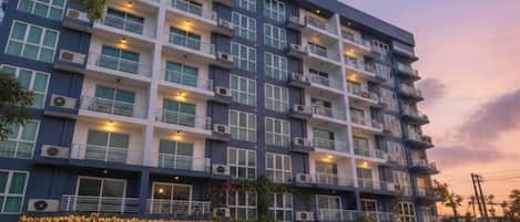 A multi-story hotel with balconies, air conditioning units, and decorative lights.