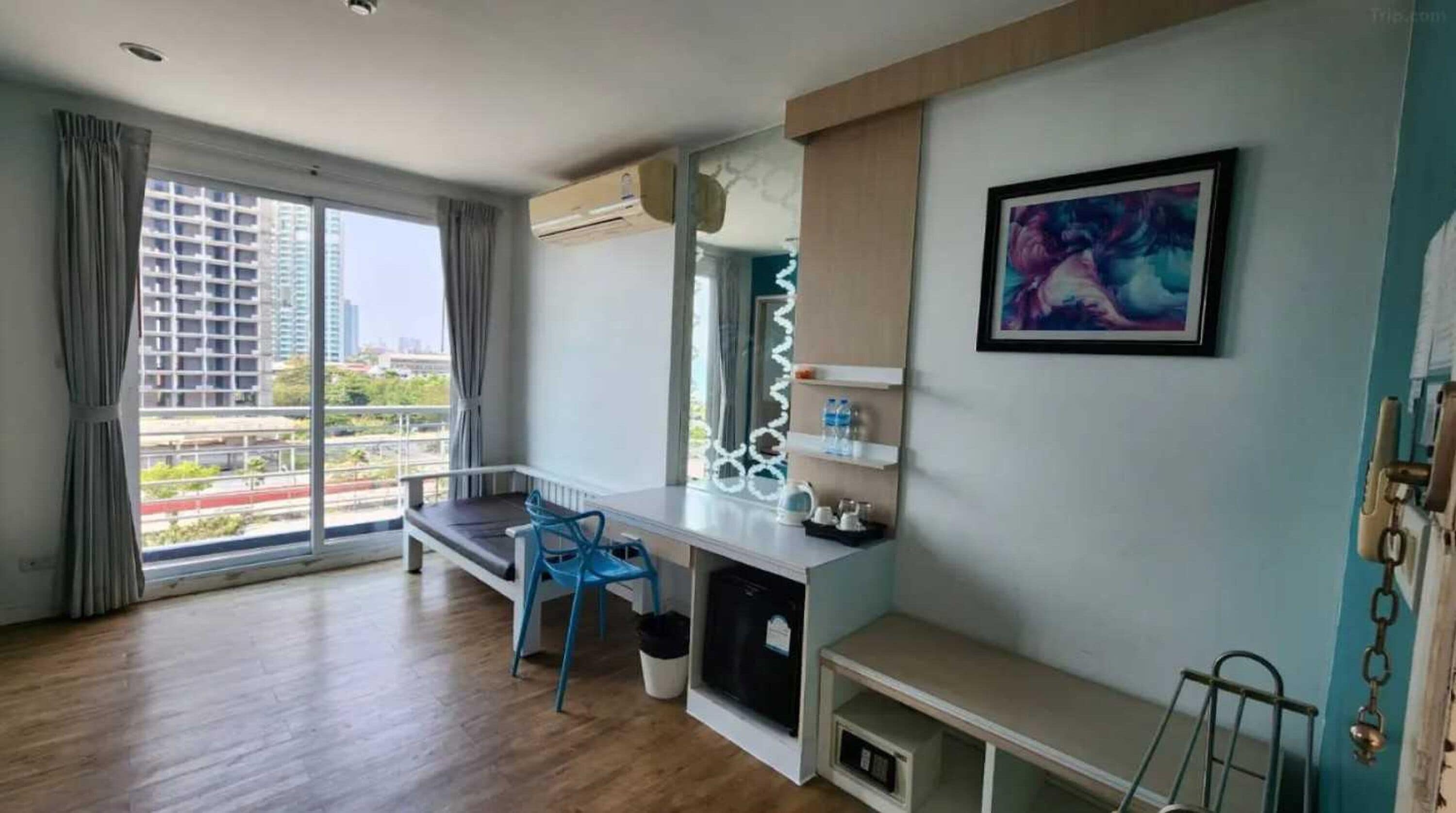 Une chambre d’hôtel moderne avec une grande fenêtre, un bureau, une chaise et un tableau au mur.