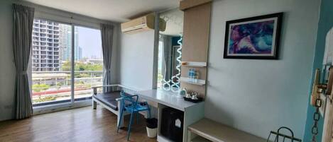 Een moderne hotelkamer met een groot raam, een bureau, een stoel en een schilderij aan de wand.