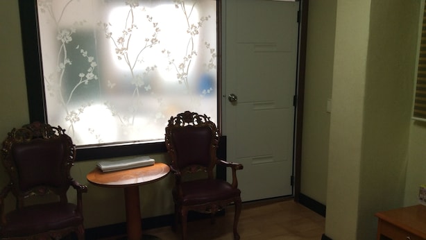 A room with two ornate chairs and a small round table, a frosted glass window with floral patterns, and a closed door. - Busan Jang Motel (Busan)