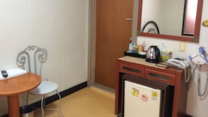 A compact hotel room with a wooden desk, a small refrigerator, a mirror, and a chair. - Busan Jang Motel (Busan)