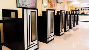 A hotel reception area with black and white framed reception desks, a large floral painting on the wall, and a clock on the wall. - Hotel Sogo Novaliches (Quezon City)