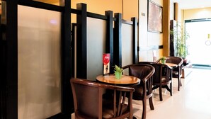 A row of wooden chairs and tables in a clean, modern interior with a glass partition and a potted plant on one table. - Hotel Sogo Novaliches (Quezon City)
