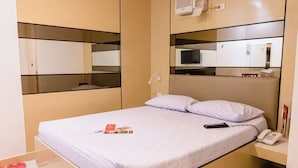 A hotel room with a bed, a bedside phone, a remote control, and a mirror on the wall. - Hotel Sogo Novaliches (Quezon City)