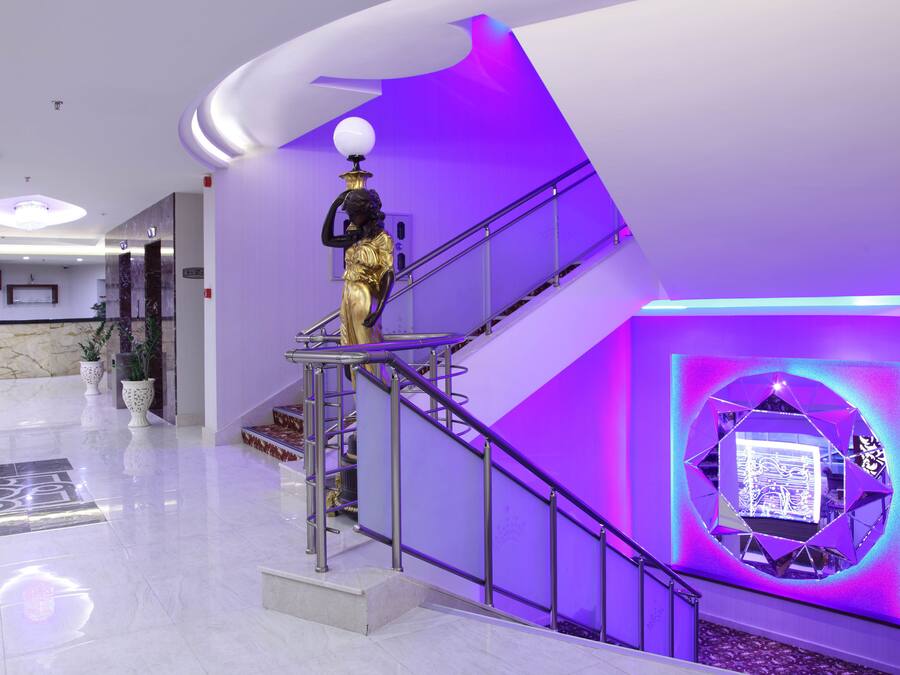 Un hall d’entrée moderne avec un sol en marbre, un escalier doté de rampes en métal et une statue décorative.