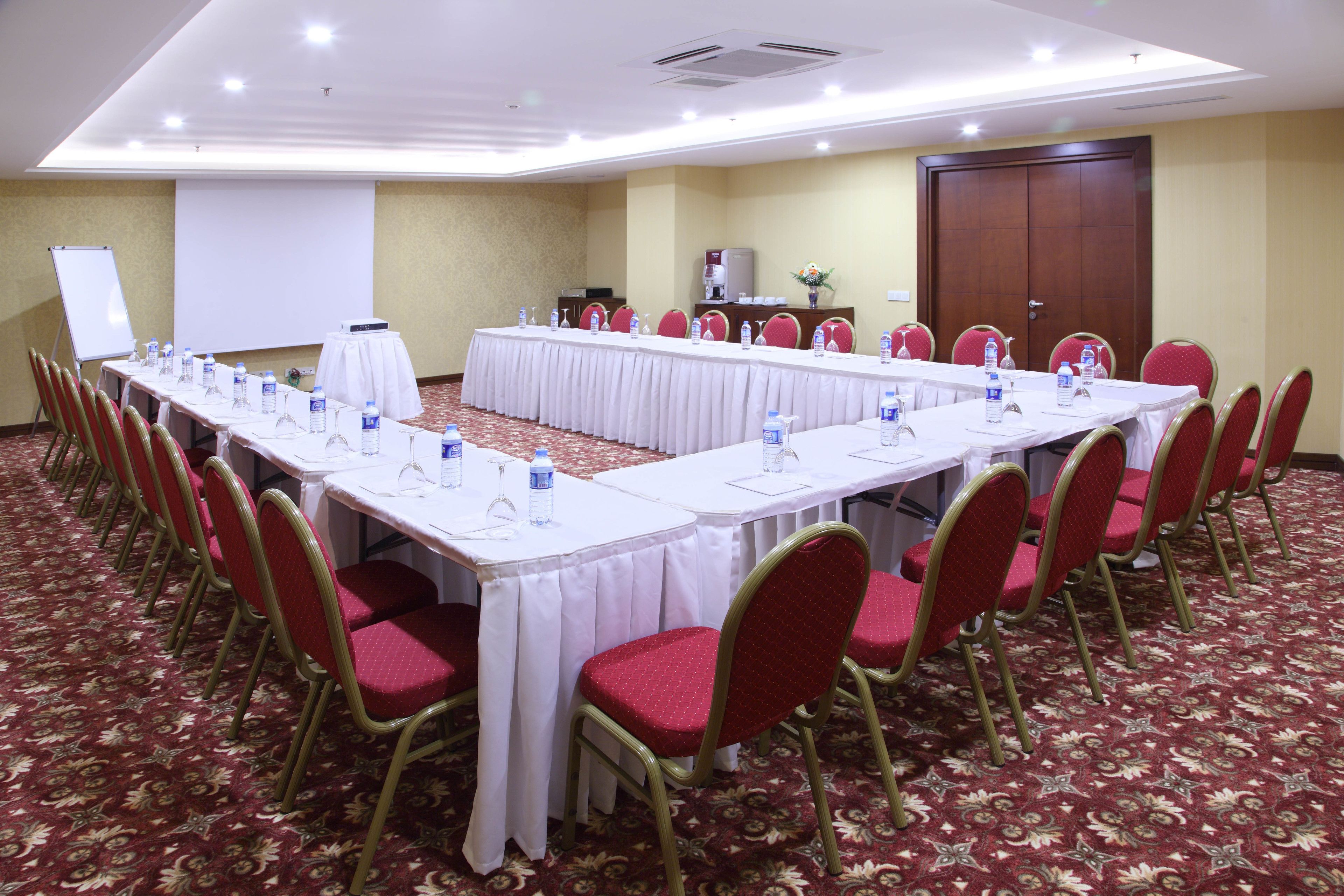 A conference room with a long table, red chairs, and a whiteboard.
