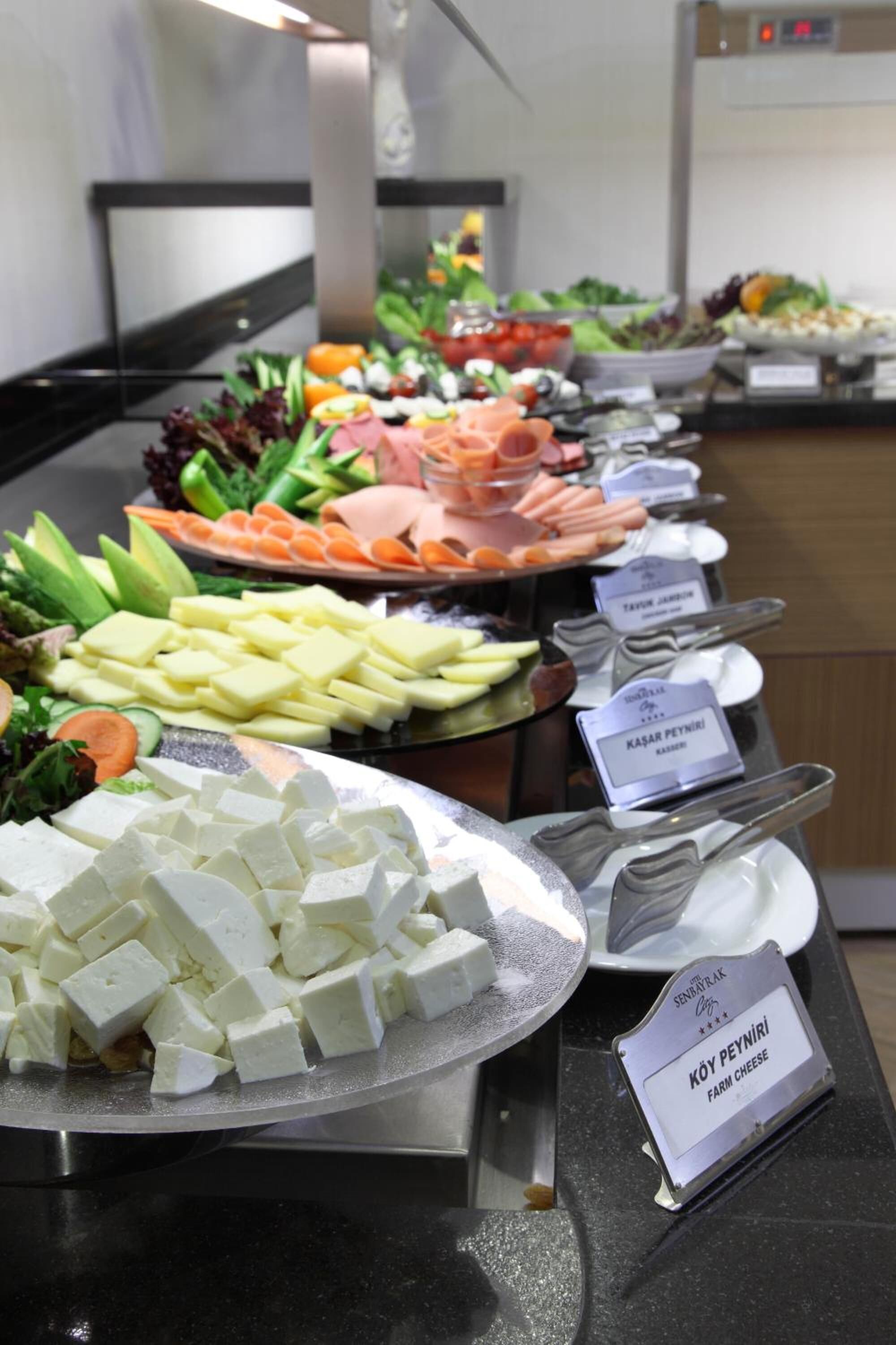 A buffet with various food items including cheese, vegetables, and meats.