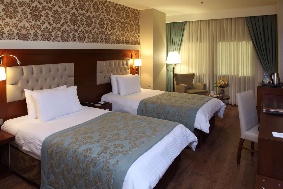 A hotel room with two beds, a desk, a chair, and a nightstand.