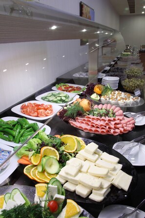 A buffet with various food items including vegetables, fruits, and cheeses.