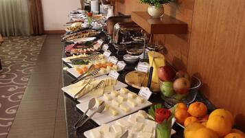 A buffet with various food items including cheese, fruits, and vegetables.