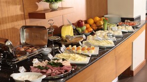 Ein reichhaltiges Buffet mit verschiedenen Speisen, darunter Obst, Käse und Fleisch.