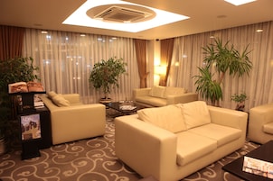 Una sala de estar moderna con un sofá, sillones, una mesa de centro y plantas en macetas.