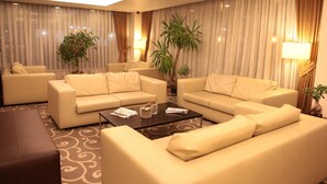 Ein modernes Wohnzimmer mit zwei Sofas, einem Couchtisch und einer großen Pflanze.