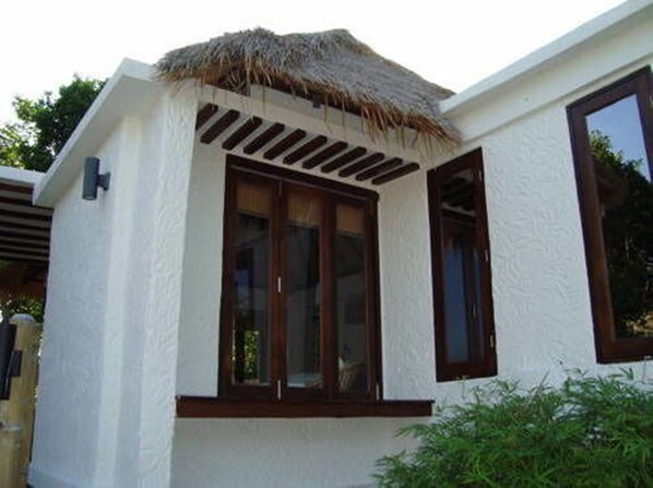 A building with a white exterior, a thatched roof, and a window with dark wooden frames. - Cape Shark Pool Villas (Koh Tao)