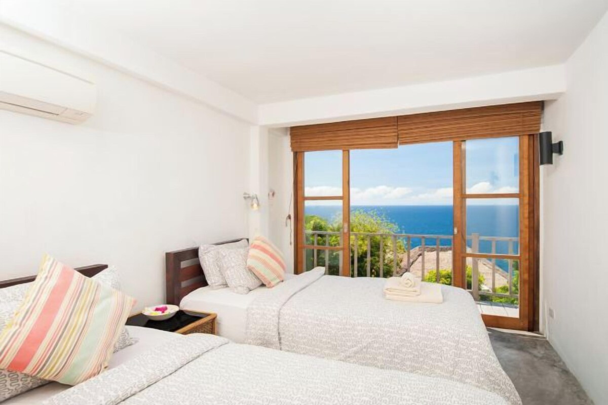 Un dormitorio con dos camas, vistas al mar y un balcón.