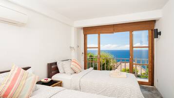 A bedroom with two beds, a view of the sea, and a balcony.