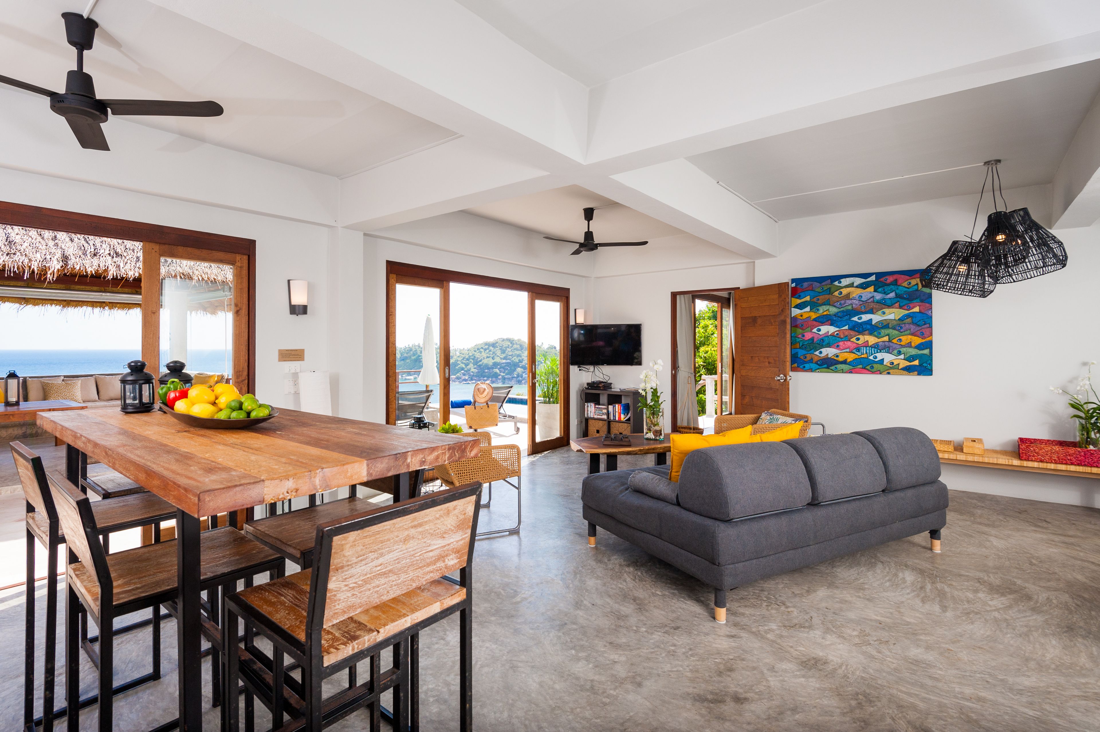 Amplia sala de estar con mesa de comedor, sofá y un gran ventanal con vistas al mar.
