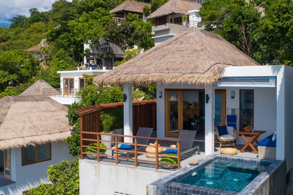 A resort with a pool, thatched-roof structures, and lush greenery.