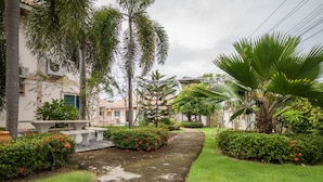 A pathway leading to a building with a covered walkway, surrounded by lush greenery and palm trees. - Narnia Resort Pattaya 2 (Sattahip)