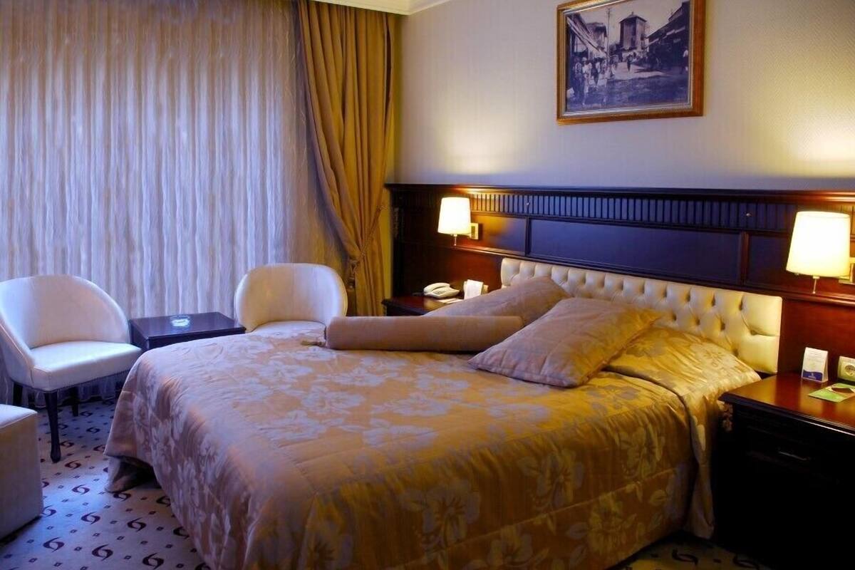 A hotel room with a large bed, two bedside tables, a chair, and a nightstand.
