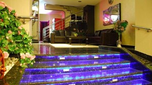 A hotel lobby with a staircase featuring illuminated steps, a reception desk, and a seating area. - Adana Erten Otel (Adana)