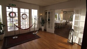Eine Hotelhalle mit roter Absperrschnur, einem Blumentopf und Blick auf den Speisesaal durch Glastüren.