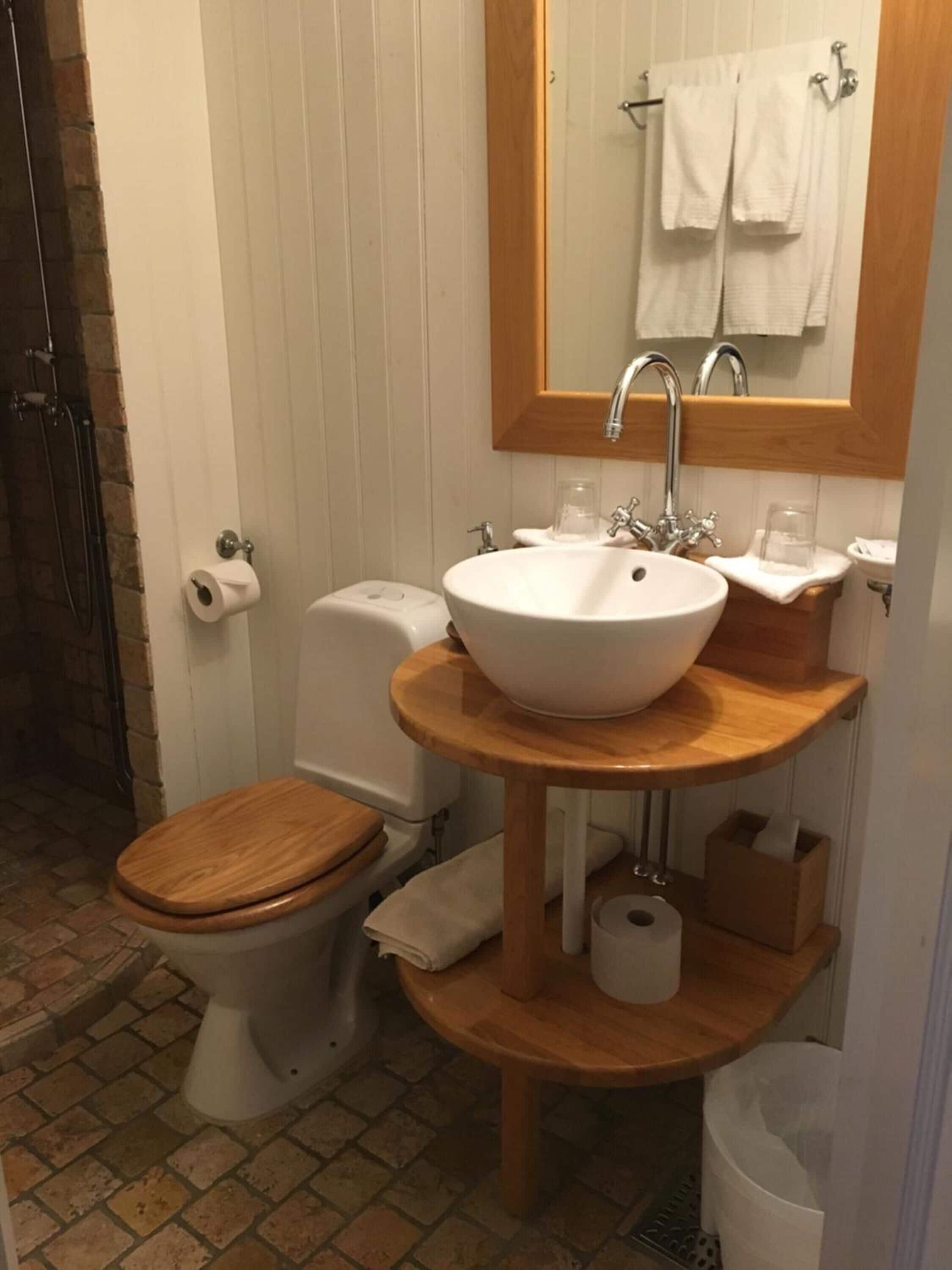 Een badkamer met een houten wastafelmeubel, een witte wastafel en een toilet.