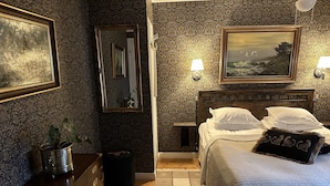 Ein Hotelzimmer mit einem hölzernen Bett, einem Schminktisch, einem Spiegel und zwei Wandlampen.