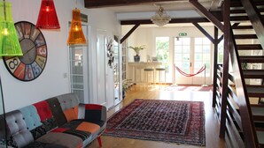 Ein geräumiger Wohnbereich mit Holzboden, einem farbenfrohen Sofa und einem großen Teppich.