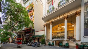 Ein Hotel mit Eingangsbereich, einer imposanten Treppe, Säulen und einem Schild mit der Aufschrift 'Sunline Hotel'.