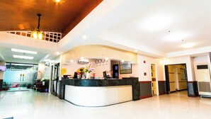 A hotel reception area with a curved reception desk, a chandelier, and a clock on the wall. - Hotel Sogo Sta Mesa (San Juan)