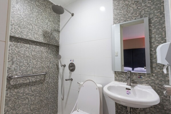 A bathroom with a shower, toilet, sink, and mirror.