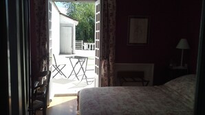 Quarto com cama, cadeira, mesa e vista para o exterior.