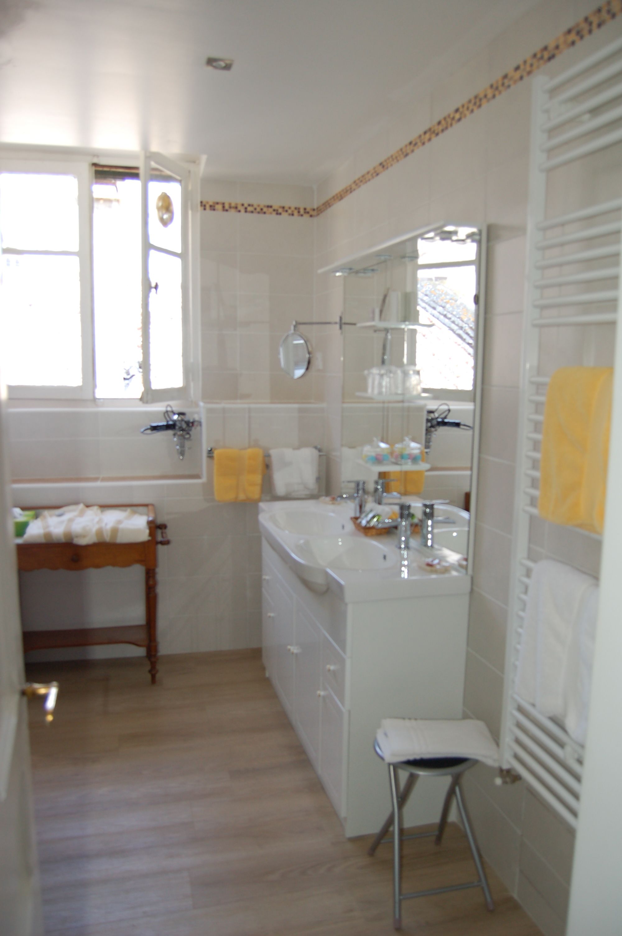A bathroom with a bathtub, sink, mirror, and a small stool.
