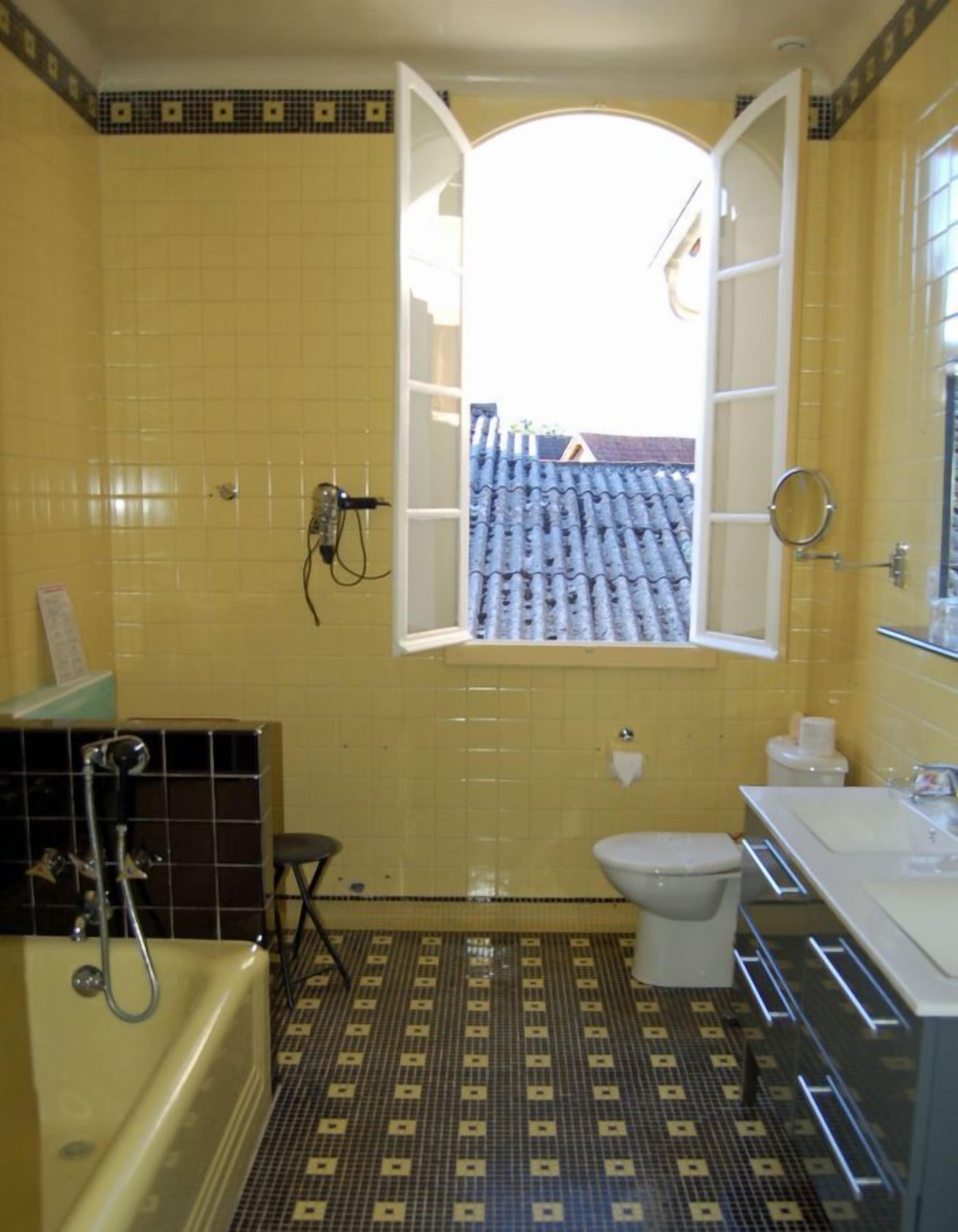 Un baño con baldosas amarillas, una bañera, un inodoro y un lavabo.