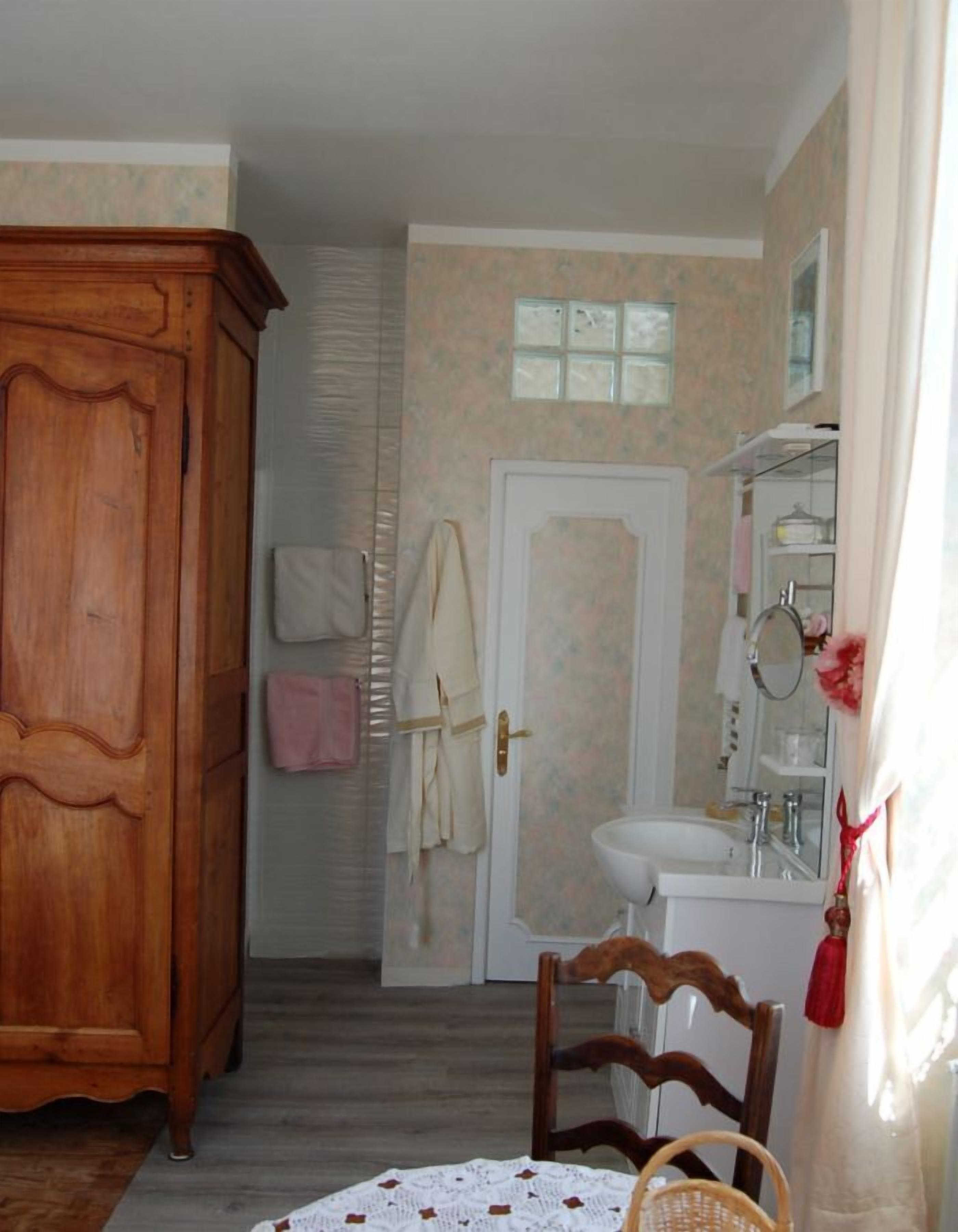 A bathroom with a wooden wardrobe, a sink, and a mirror.