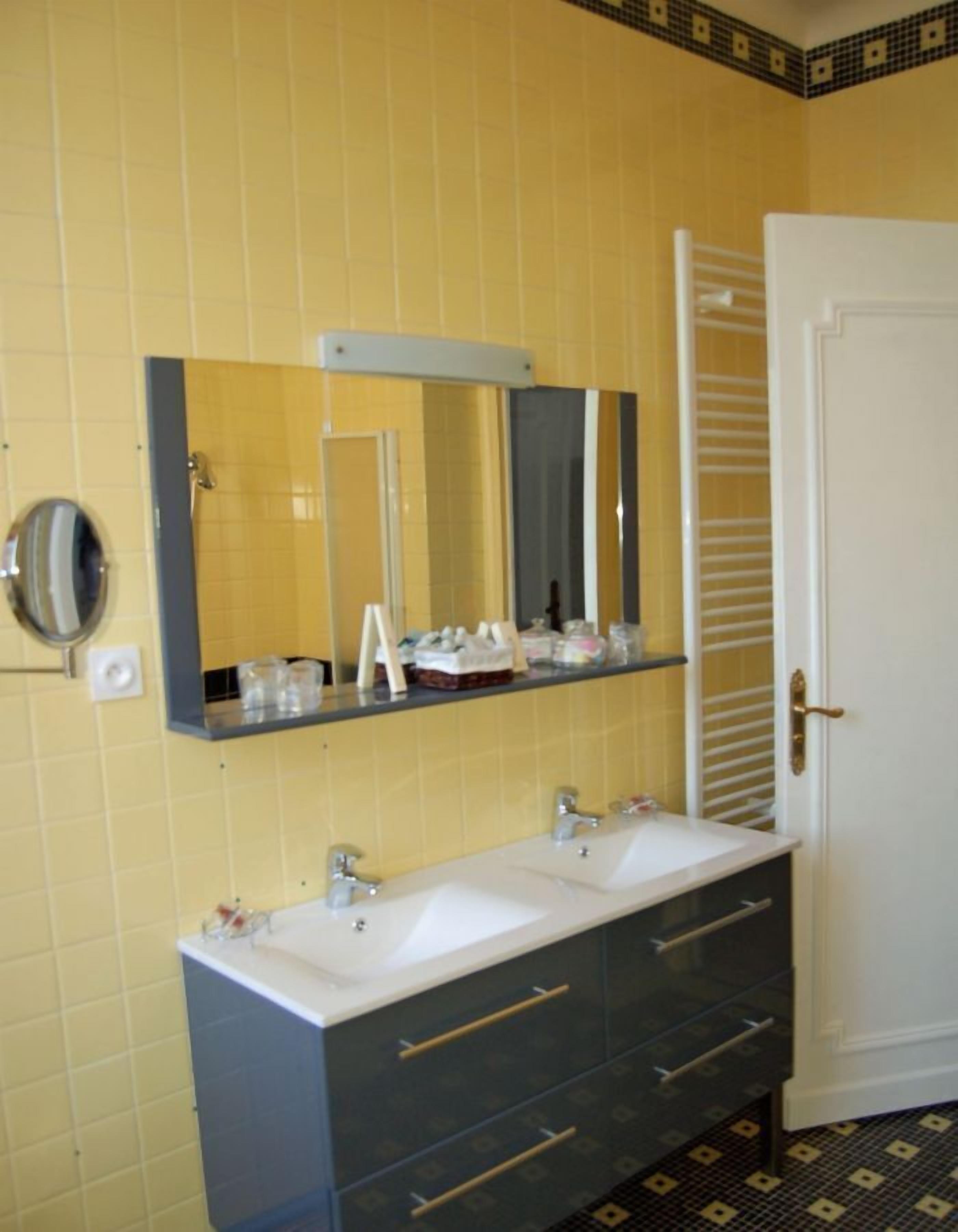 A bathroom with two sinks, a mirror, and a towel rack.