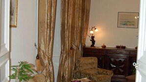 Um corredor com tapete estampado, um armário de madeira e uma mesa com cadeiras.