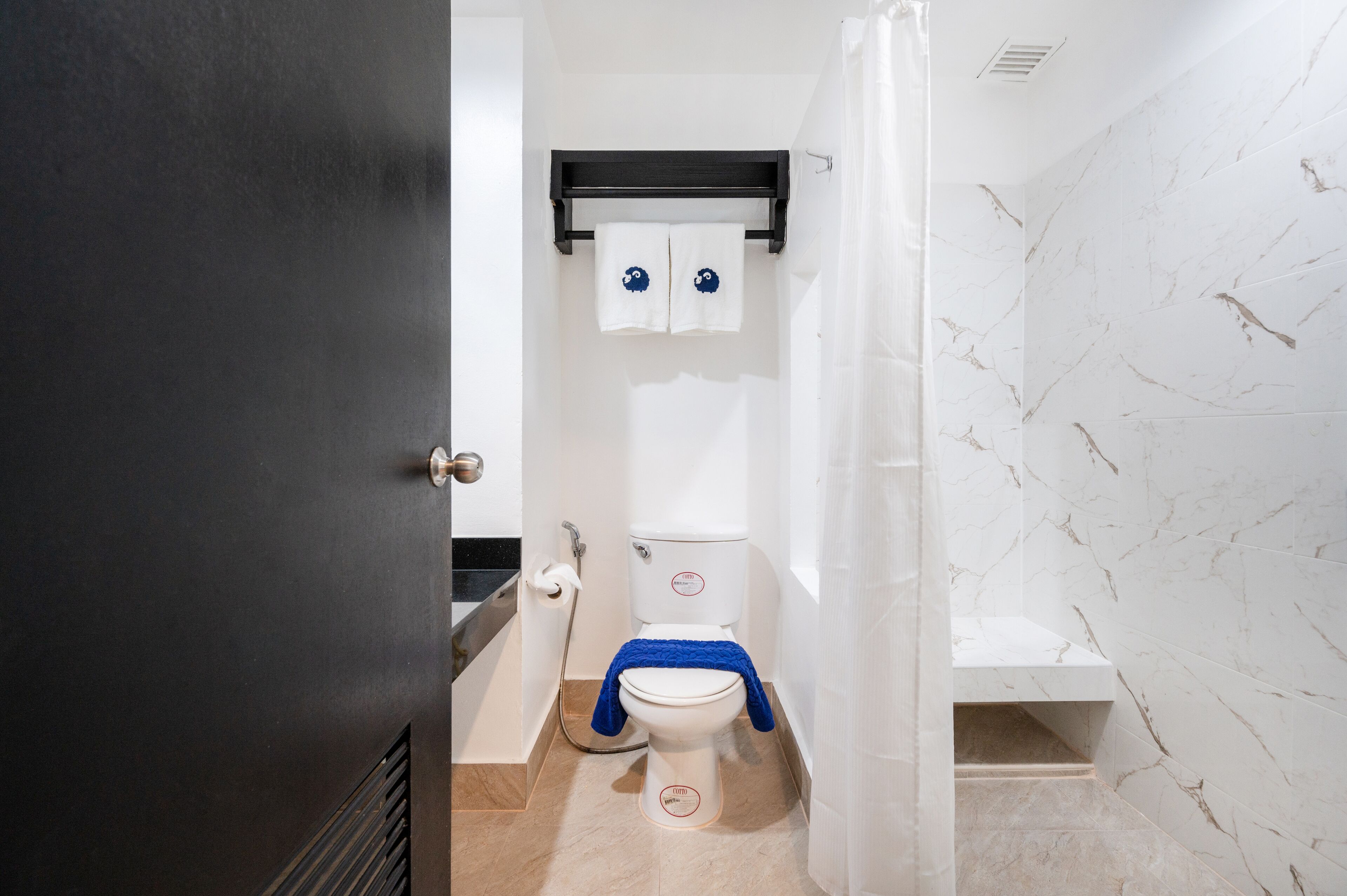 A bathroom with a toilet, a towel rack, and a shower area.