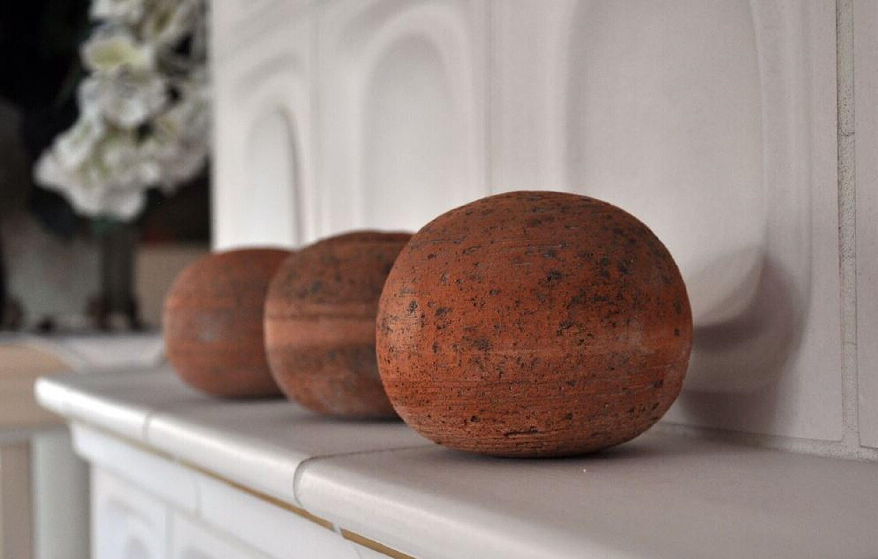 Three spherical objects on a white mantelpiece.