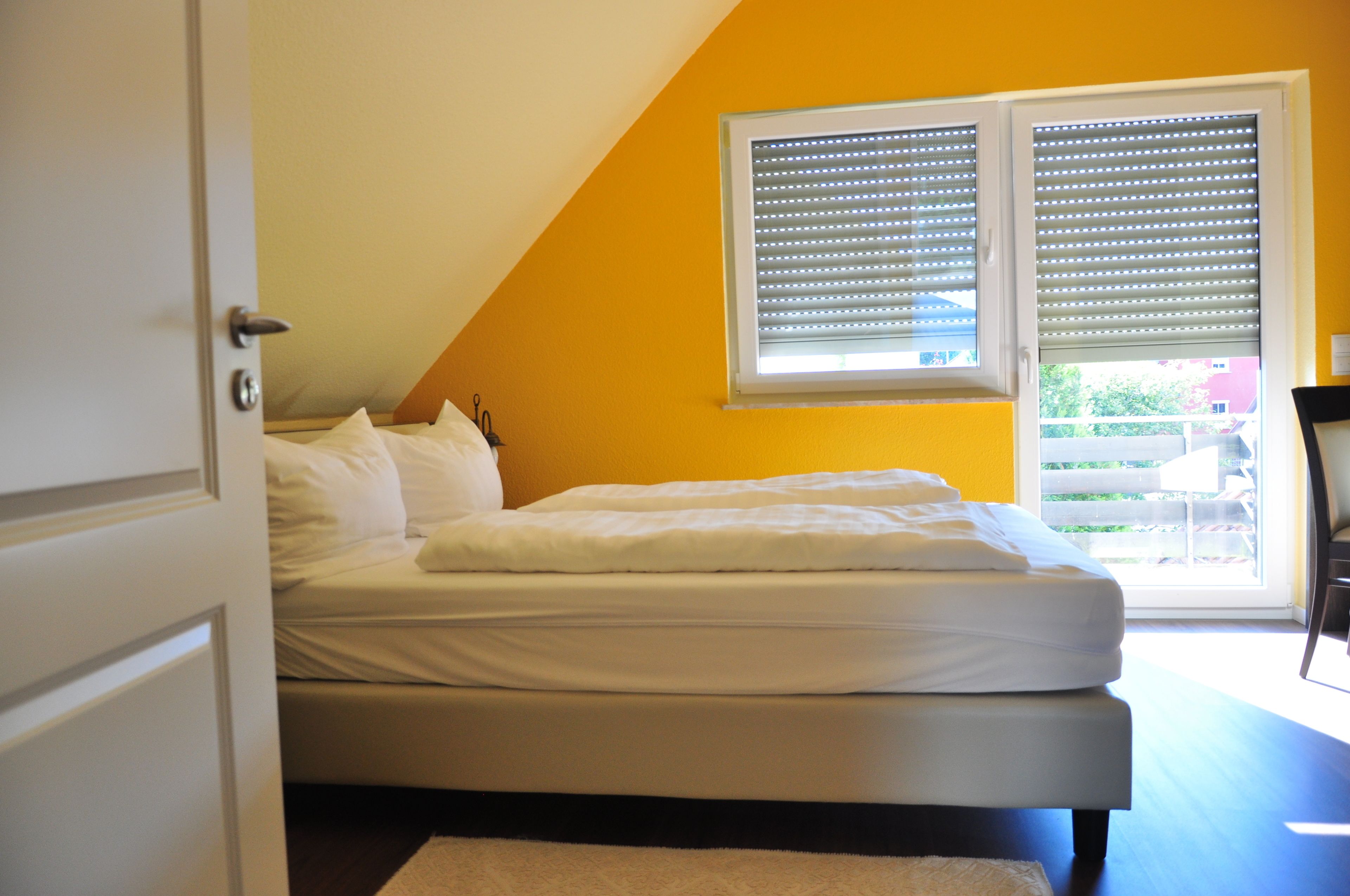 A bedroom with a bed, a window with blinds, and a view of the outside.